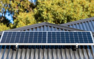 solar power system panels on dark grey colorbond roof with gum trees in the background