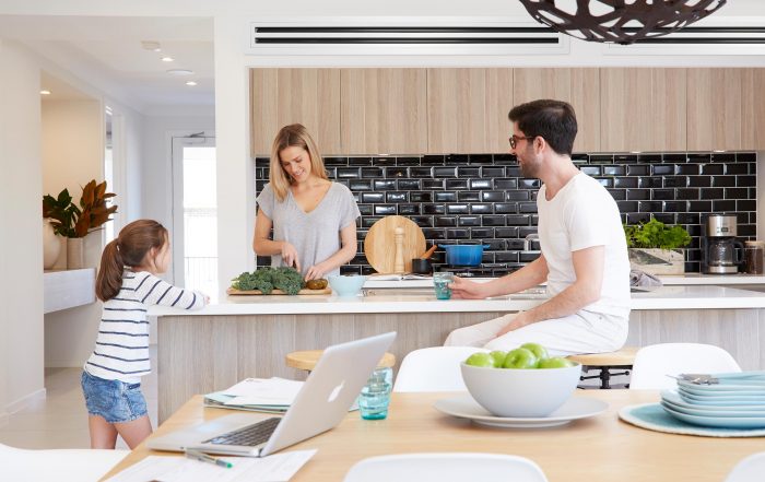 Family of 3 enjoying time in modern kitchen with air conditioning ducts in ceiling