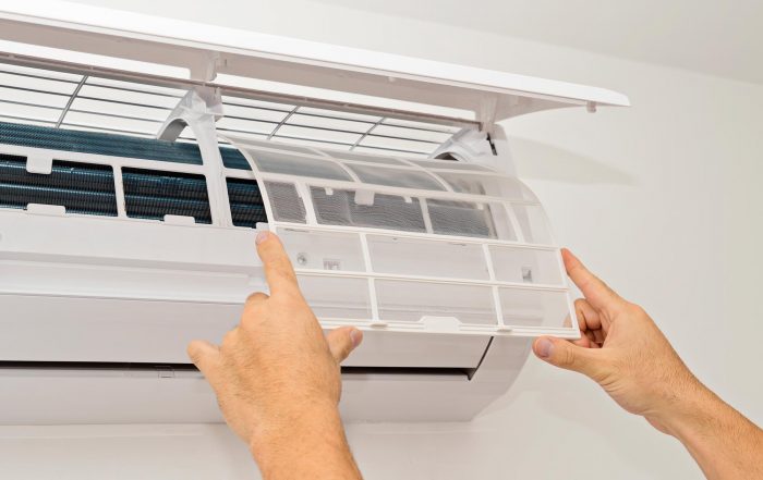 Man fitting clean filter back onto wall mounted split system air conditioner